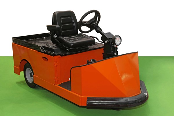 An orange electric tow tug with a black seat, steering wheel, and headlight on a green floor with a white background.