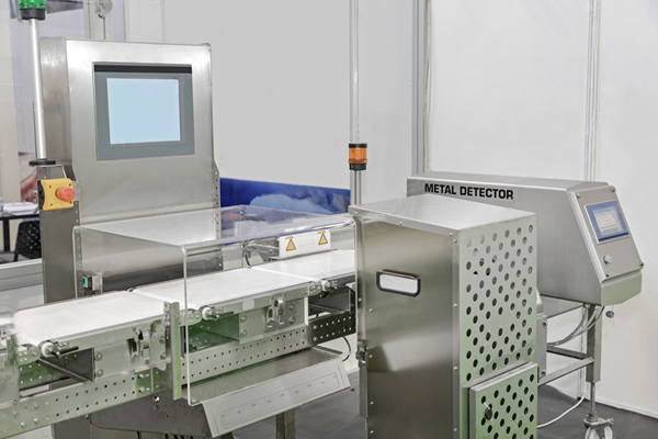  an industrial conveyor system with a metal detector and checkweigher, designed for detecting and rejecting products with metal contaminants in food production.