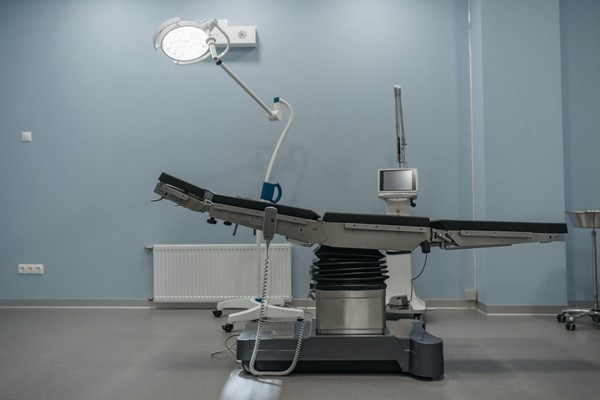 Empty adjustable medical treatment table in a clinical setting.